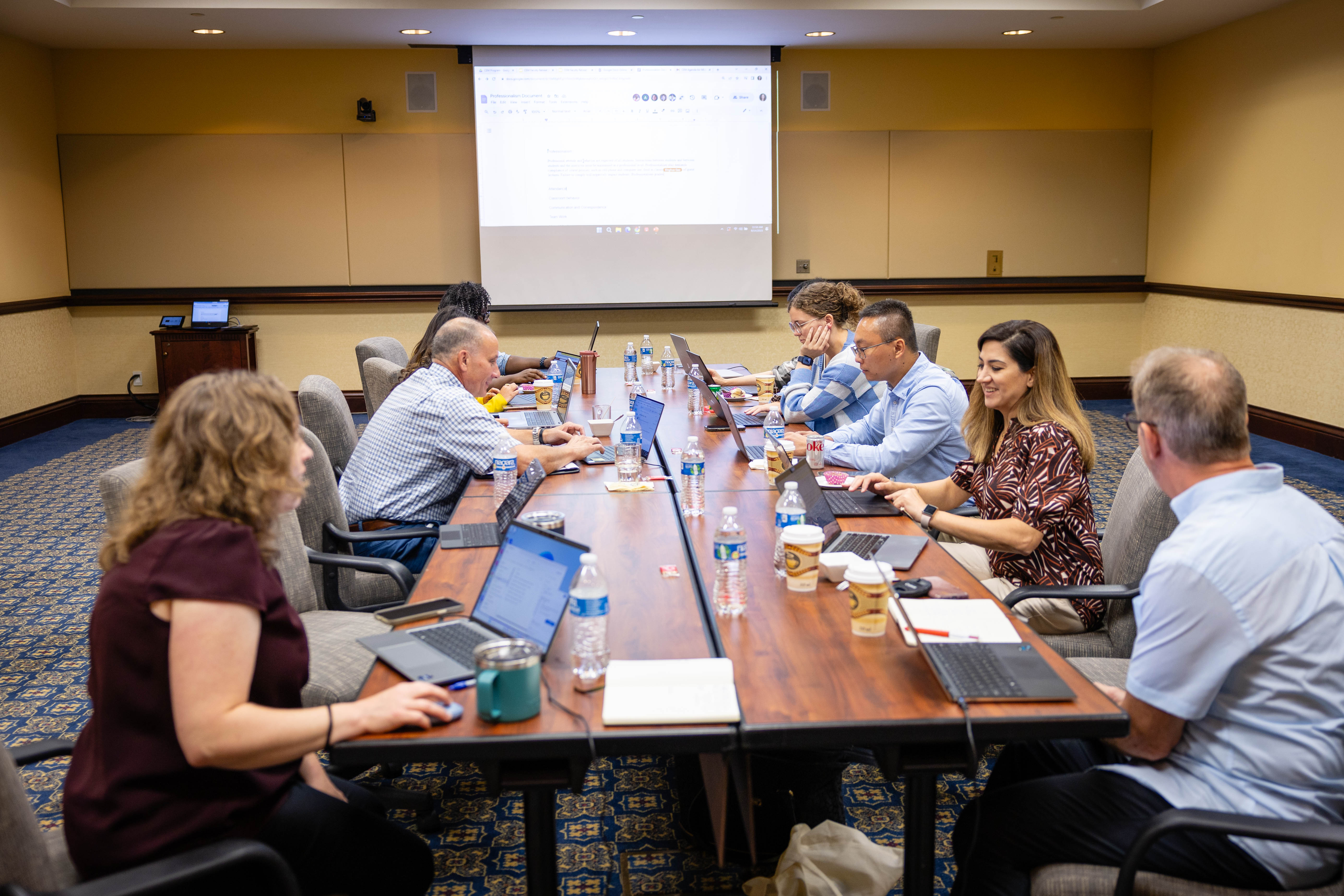 A group of people sit and work on their laptops