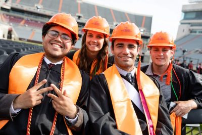 Students wear hardhats at their graduation ceremony.