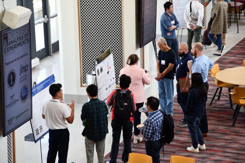 Groups of individuals stand around various posters in the Data & Decision Sciences atrium.