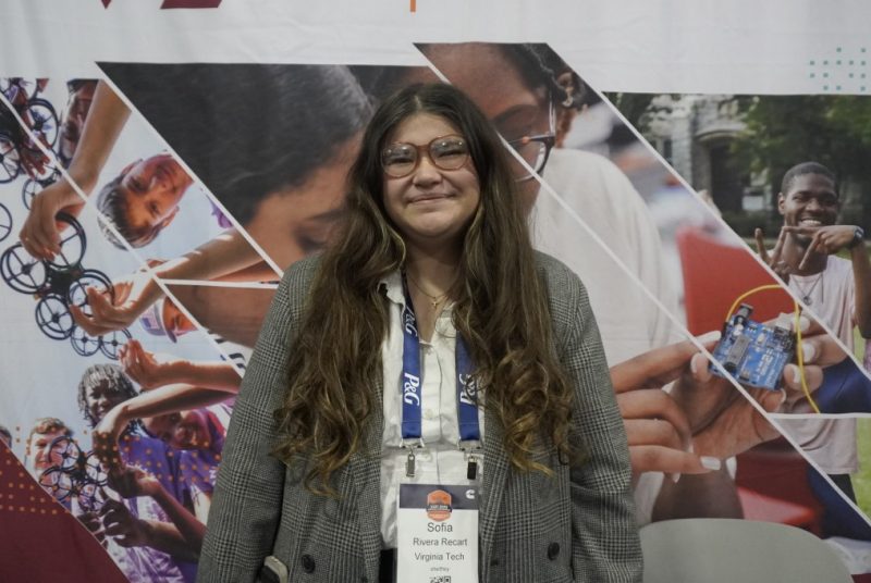 Sofia Rivera Recart attends the Society of of Hispanic Professional Engineers Conference while smiling as she stands in front of a Virginia Tech Engineering banner.