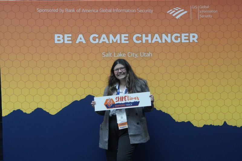 Sofia Rivera Recart attends the Society of of Hispanic Professional Engineers Conference as she stand in front of a "be a game changer" sign.