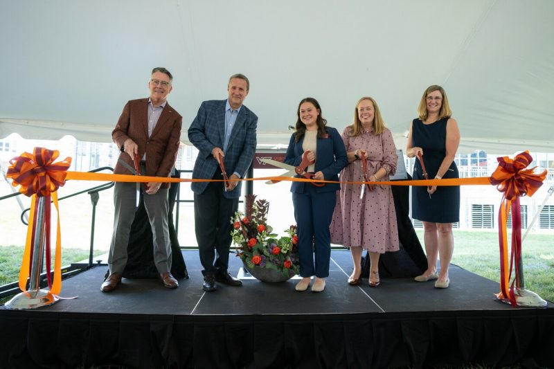 Five people cut a ribbon during Hitt Hall dedication.