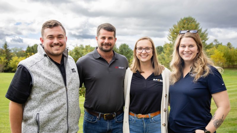 Young Alumni Committee Leaders (from left to right) Jacob Lescault, Sam Savoia, Allie Vogrig, Danielle Hill standing outside on a cloudy day while smiling.