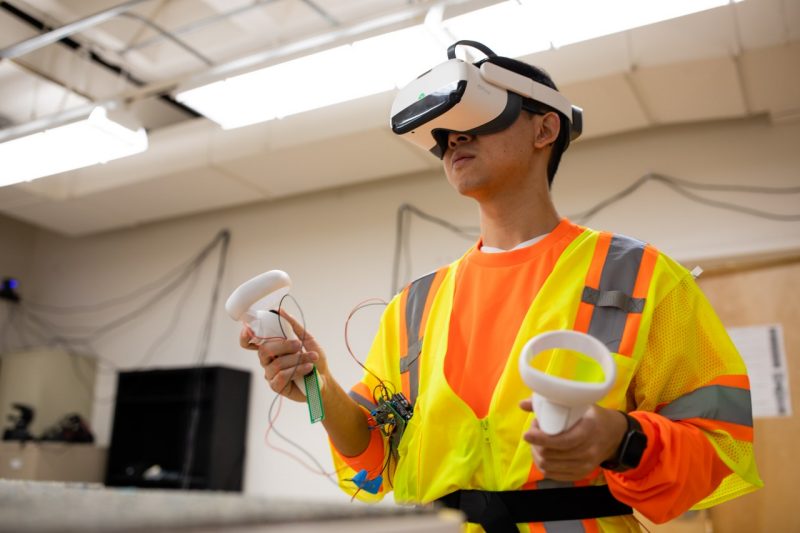 A student wears a vest and VR headset.