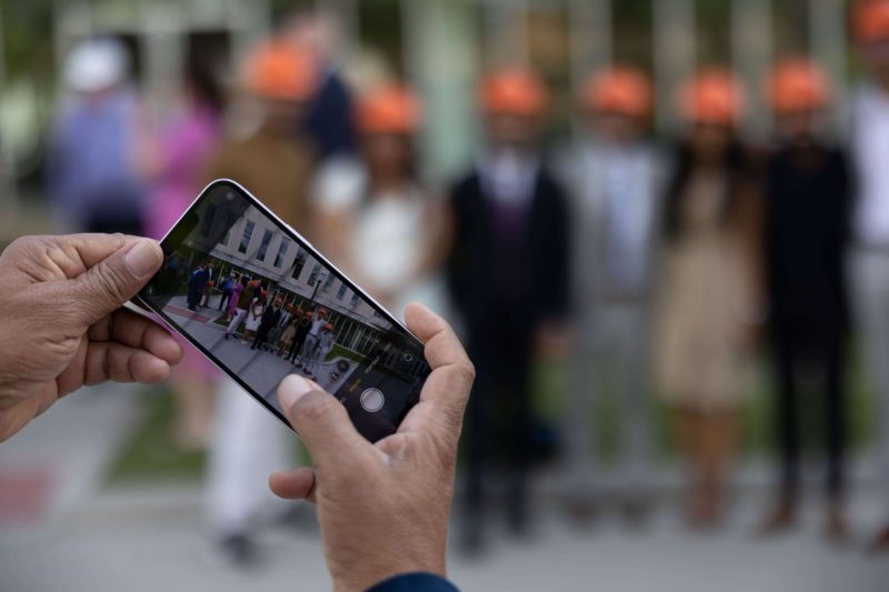 A person takes a photo of a group of graduates.